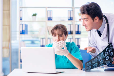 Two doctors discussing x-ray MRI image in hospitalの写真素材