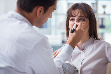 Plastic surgeon preparing for operation on woman faceの写真素材