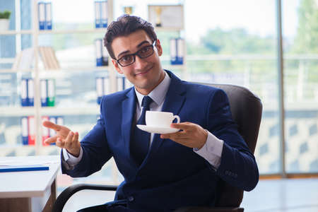 Businessman drinking coffee in the office during breakの写真素材