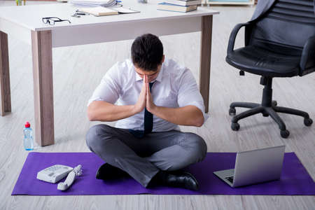 Man meditating in the office to cope with stressの写真素材