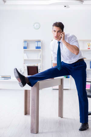 Young businessman doing sports stretching at workplaceの写真素材