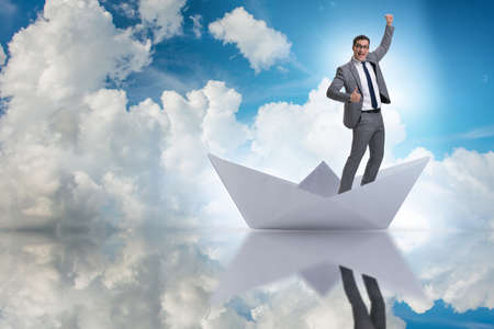 Excited businessman riding paper ship boatの写真素材