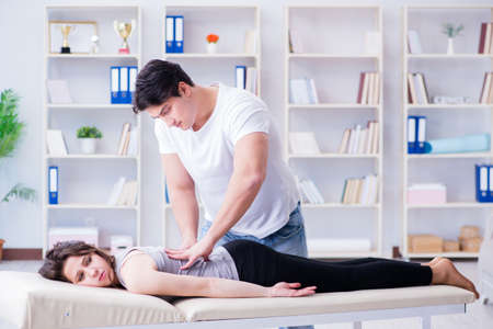 Young doctor chiropractor massaging female patient womanの写真素材