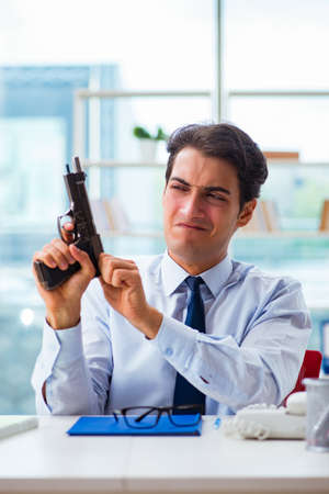 Angry businessman with gun thinking of committing suicideの写真素材