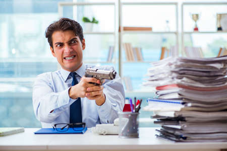 Angry businessman with gun thinking of committing suicideの写真素材
