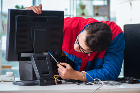 Computer repairman working on repairing computer in IT workshopの写真素材