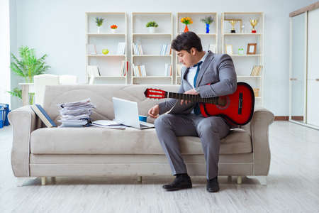 Businessman playing guitar at homeの写真素材