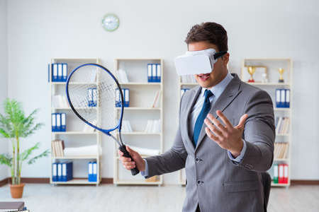 Businessman playing virtual reality tennis in office with VR gogの写真素材
