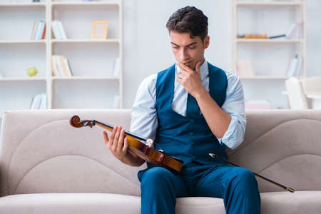 Young musician man practicing playing violin at home