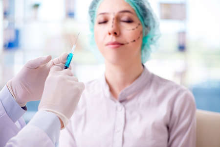 Plastic surgeon preparing for operation on woman faceの写真素材