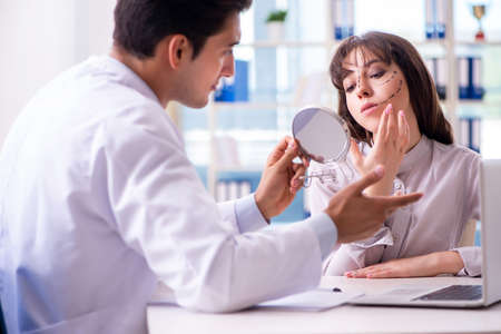 Plastic surgeon preparing for operation on woman faceの写真素材