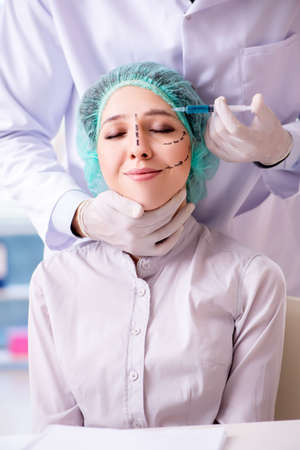 Plastic surgeon preparing for operation on woman faceの写真素材