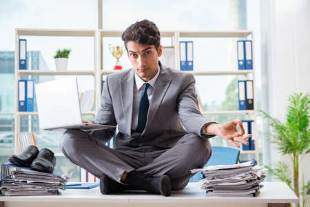 Businessman sitting on top of desk in officeの写真素材