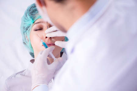 Plastic surgeon preparing for operation on woman faceの写真素材