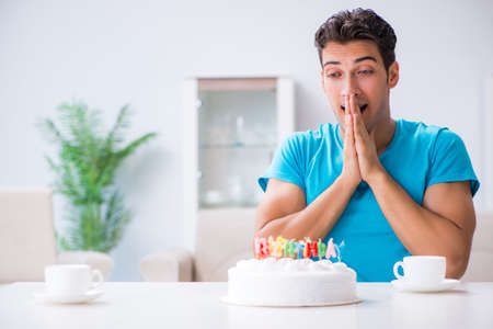 Young man celebrating birthday alone at homeの写真素材