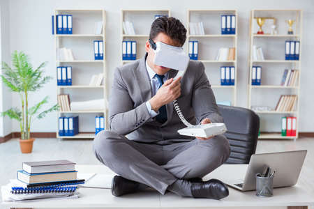 Businessman in virtual reality VR glasses meditating at desk topの写真素材