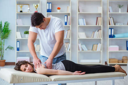 Young doctor chiropractor massaging female patient womanの写真素材