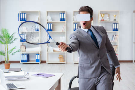 Businessman playing virtual reality tennis in office with VR gogの写真素材