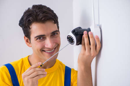 Contractor installing surveillance CCTV cameras in officeの写真素材