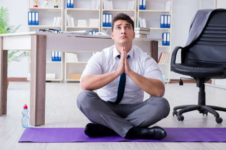 Man meditating in the office to cope with stressの写真素材