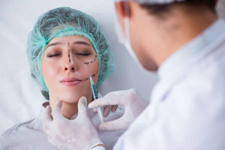 Plastic surgeon preparing for operation on woman faceの写真素材