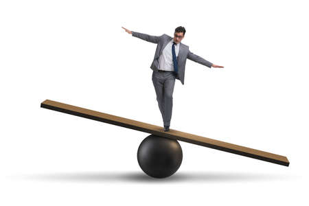 Businessman balancing on seesaw in uncertainty conceptの写真素材