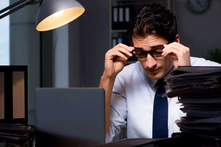 Young businessman working overtime late in officeの写真素材