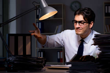 Young businessman working overtime late in officeの写真素材