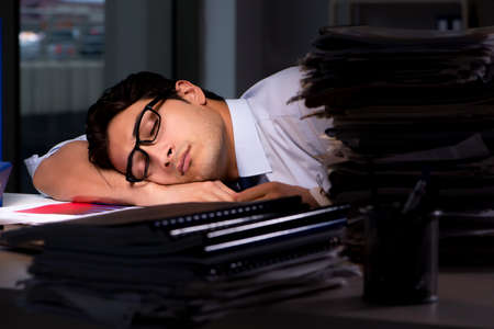 Young businessman working overtime late in officeの写真素材