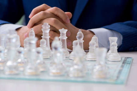Young businessman playing glass chess in officeの写真素材