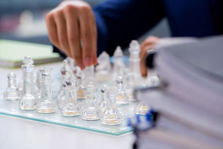 Young businessman playing glass chess in office