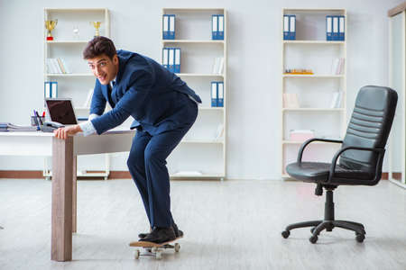 Young businessman with skate in office in sports conceptの写真素材