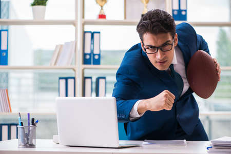 Businessman with american football in officeの写真素材