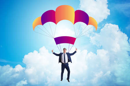Young businessman falling on parachute in business conceptの写真素材