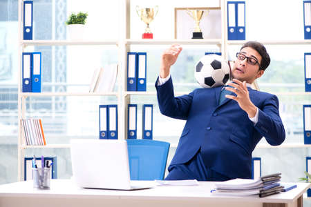 Businessman playing football in the officeの写真素材