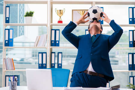 Businessman playing football in the officeの写真素材
