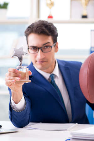 Businessman with american football in officeの写真素材