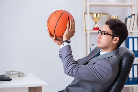 Young businessman playing basketball in office during breakの写真素材