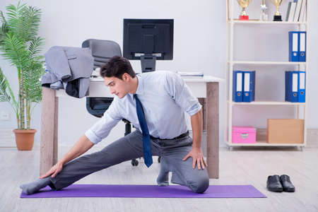 Businessman doing sports in office during breakの写真素材