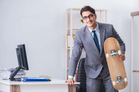 Young businessman riding skate in office during breakの写真素材