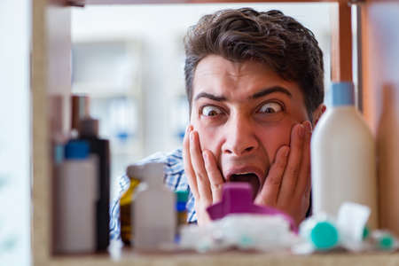 Sick ill man looking for medicines at farmacy shelfの写真素材
