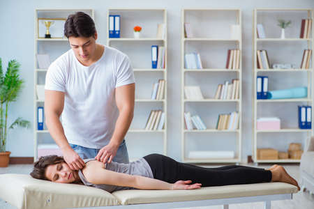 Young doctor chiropractor massaging female patient womanの写真素材