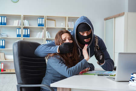 Criminal taking businesswoman as hostage in officeの写真素材