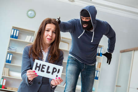 Criminal taking businesswoman as hostage in officeの写真素材