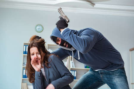 Criminal taking businesswoman as hostage in officeの写真素材