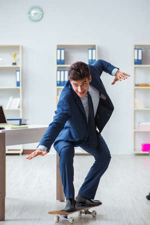Young businessman with skate in office in sports conceptの写真素材