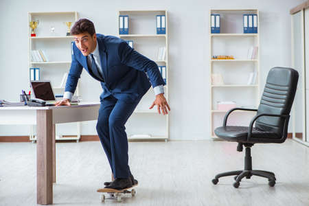 Young businessman with skate in office in sports conceptの写真素材