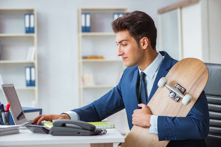 Young businessman with skate in office in sports conceptの写真素材
