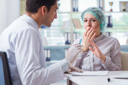 Plastic surgeon preparing for operation on woman faceの写真素材