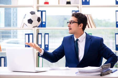 Businessman playing football in the officeの写真素材